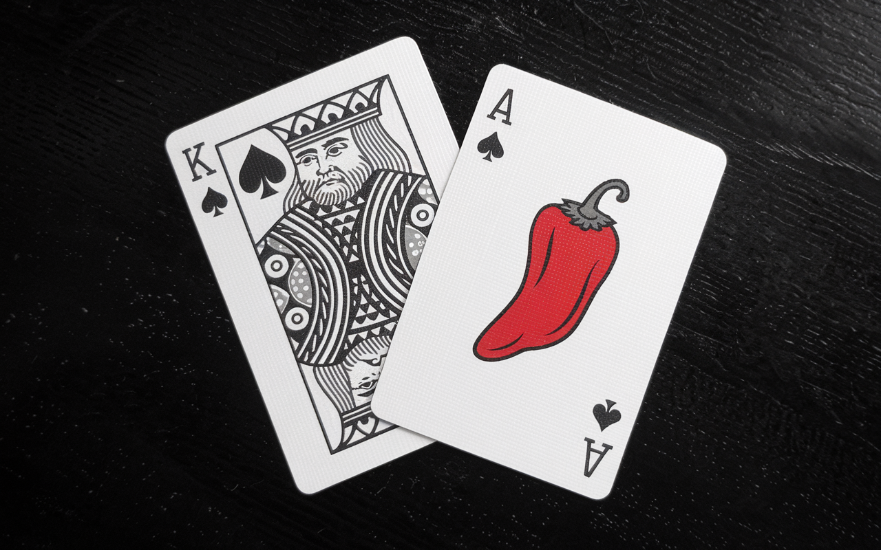 Black and white photo black jack cards. The ace has a red chili pepper in the middle