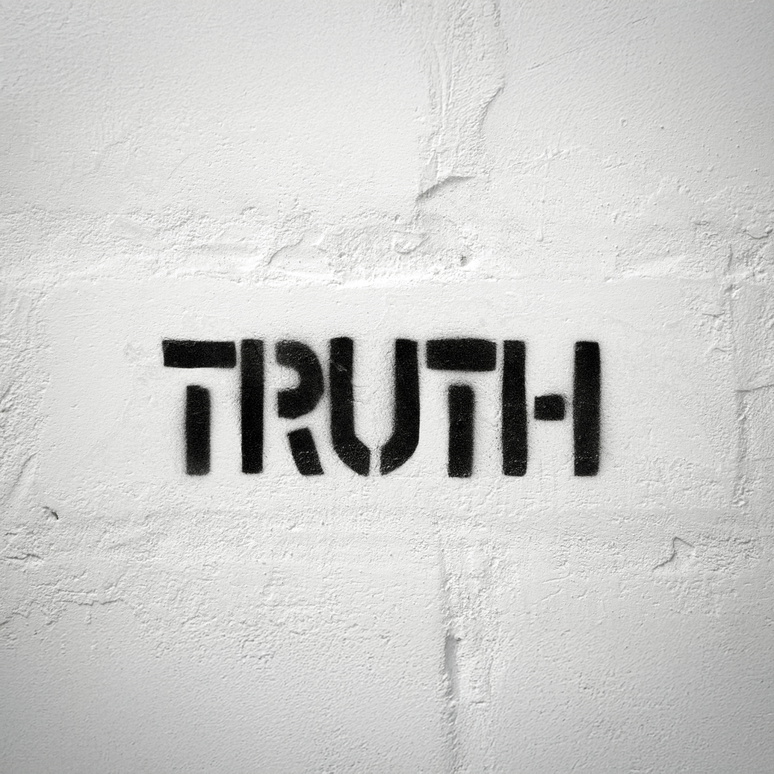 truth spray painted in black on a white wall.