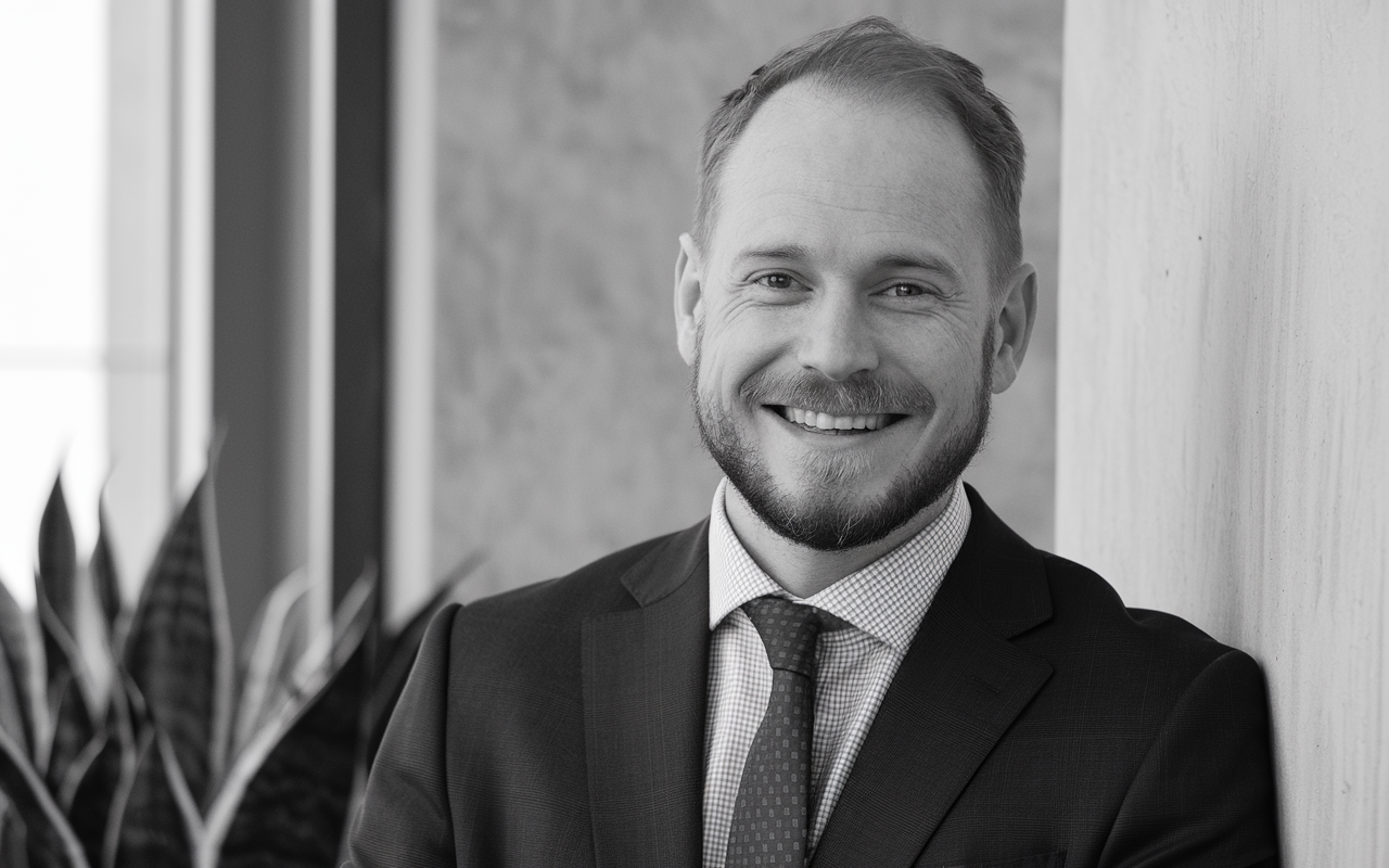 Middle aged white male starting to bald smiling in a suite and tie. Black and White photo portrait.
