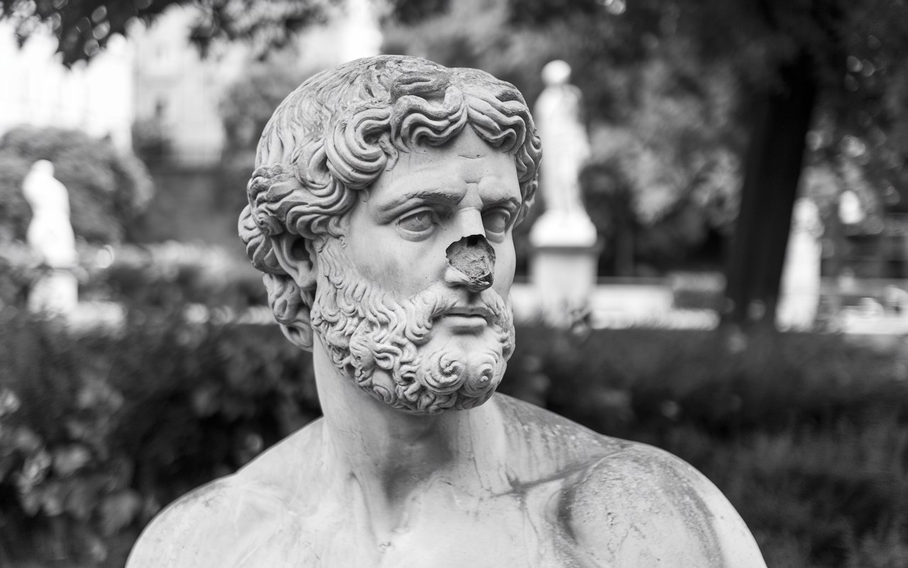 Greek God Statue that is broken. The statues nose is missing.